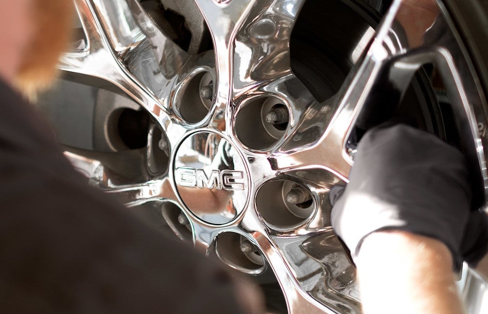 Service technician holding a chrome alloy wheel during a tire service